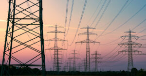 Power lines in a field at dusk with a sunset in the background