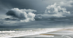 View from a beach as storm clouds approach land.