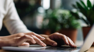 A person types on a laptop at a desk.
