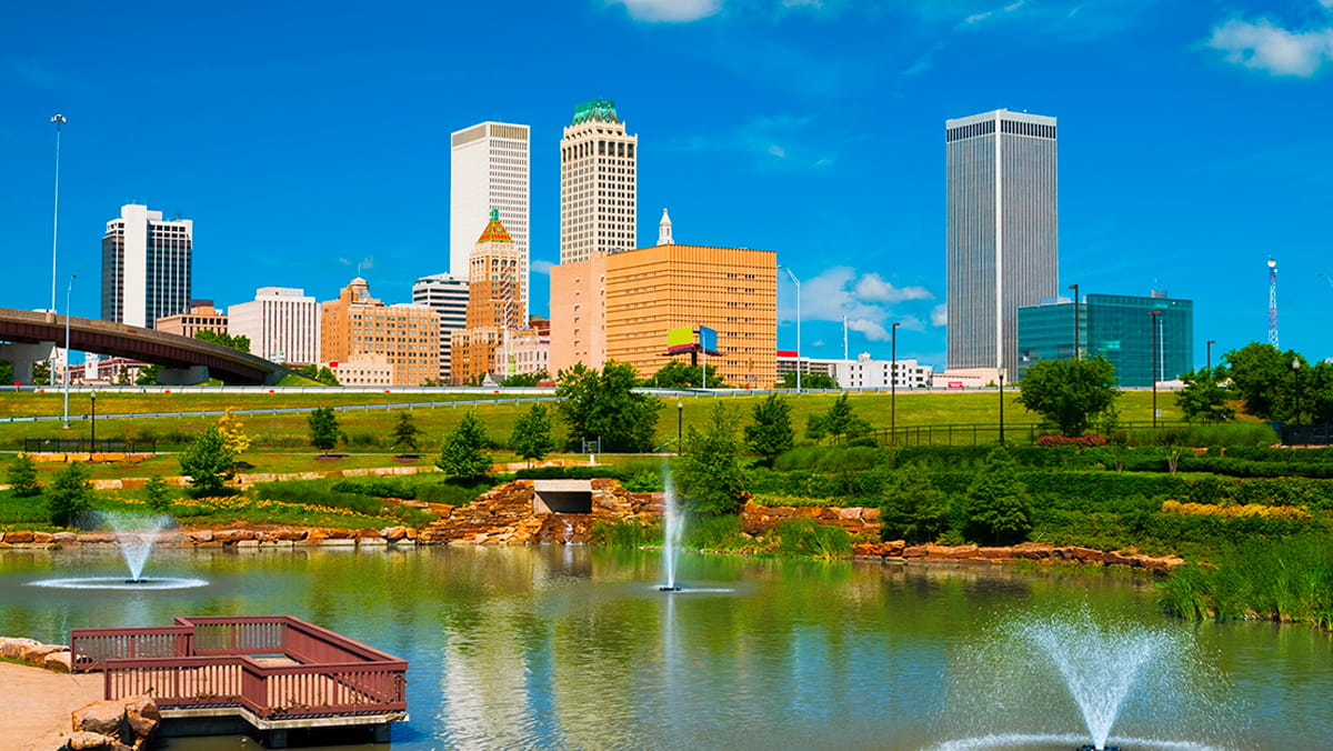 A photo of the Tulsa, OK, skylines with a pond and pier in the foreground.