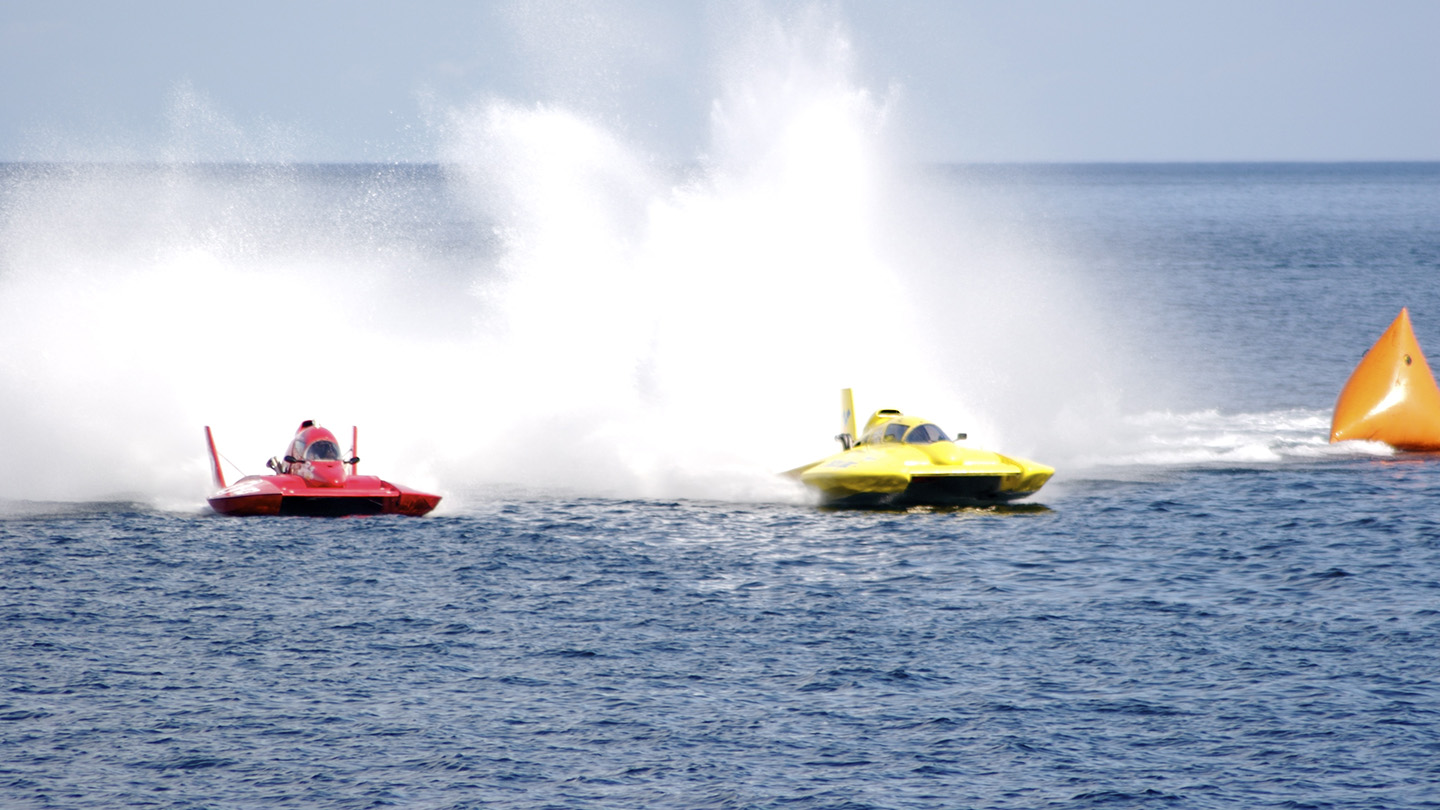 3 racing boats traverse open water.