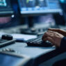 A person types on a keyboard in a security operations and surveillance center.