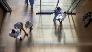 Patients and doctors walk in and out of a hospital entrance.