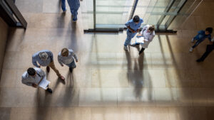 Patients and doctors walk in and out of a hospital entrance.