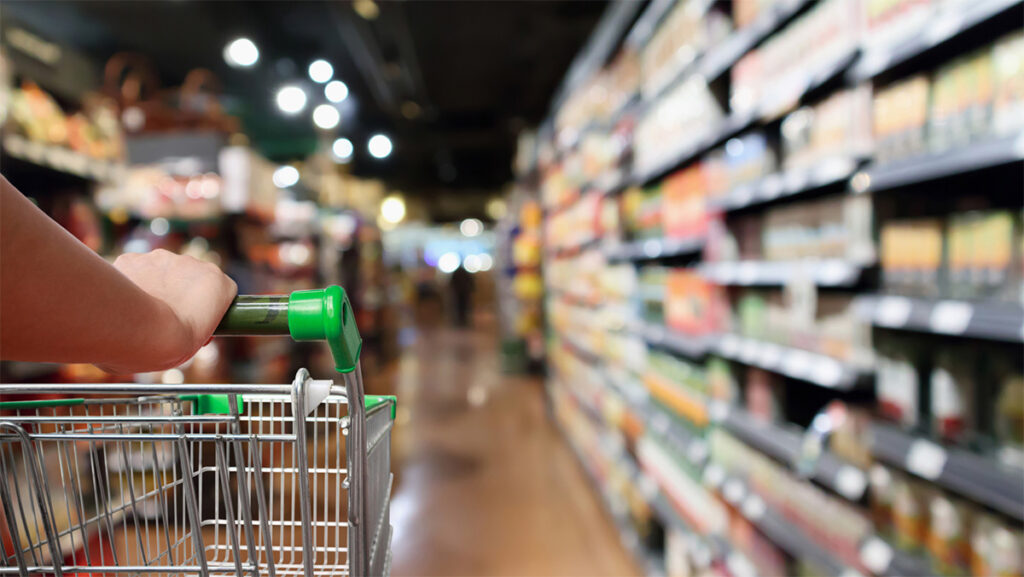 A person walks down an aisle in a supermarket.