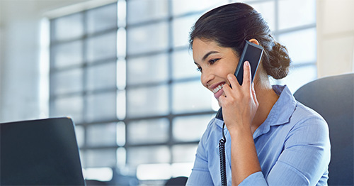 A woman talks on the phone with a client.