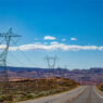 Power transmission pylpns standing alongside a road in the US Southwestern desert.