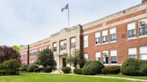 The front of a grade school with shrubs and a lawn in front.