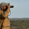 A man views a landscape through binoculars.