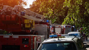 A fleet of fire trucks and police cruisers parked on a street.