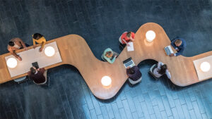 People working in various places around a long, winding table.
