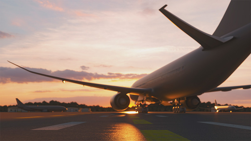 A view of a jet moving across an airfield at sunset.