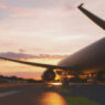 A view of a jet moving across an airfield at sunset.