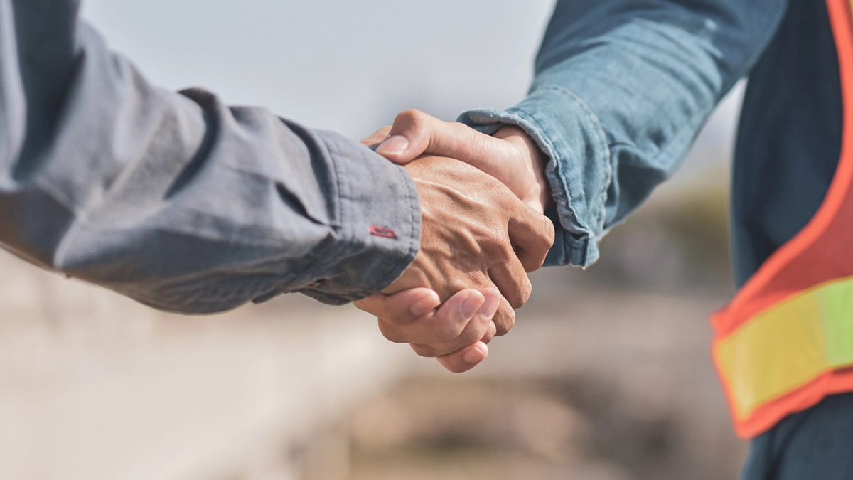 Two people shake hands on a worksite.